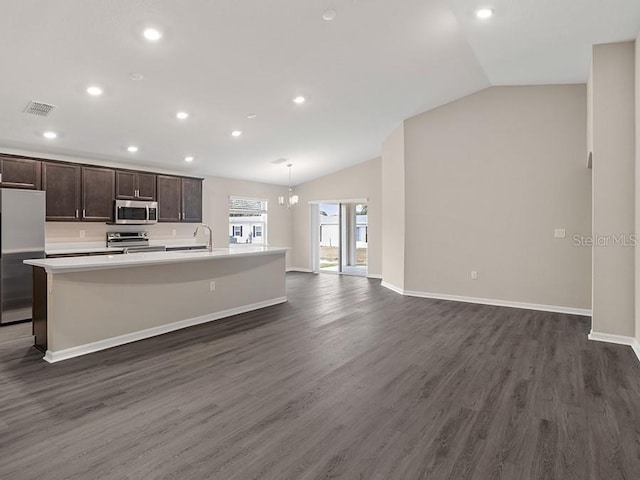 kitchen featuring dark hardwood / wood-style flooring, stainless steel appliances, vaulted ceiling, decorative light fixtures, and an island with sink