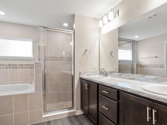 bathroom with plenty of natural light, independent shower and bath, wood-type flooring, and vanity