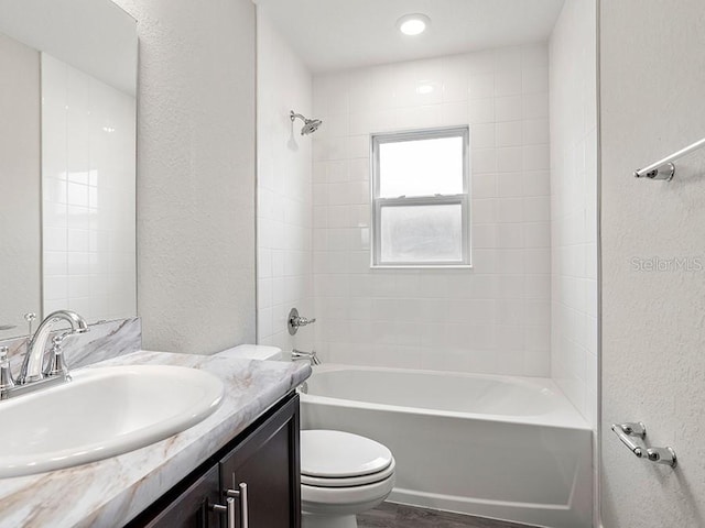 full bathroom with vanity, wood-type flooring, tiled shower / bath combo, and toilet