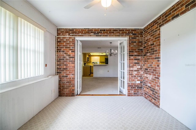 unfurnished sunroom featuring ceiling fan with notable chandelier