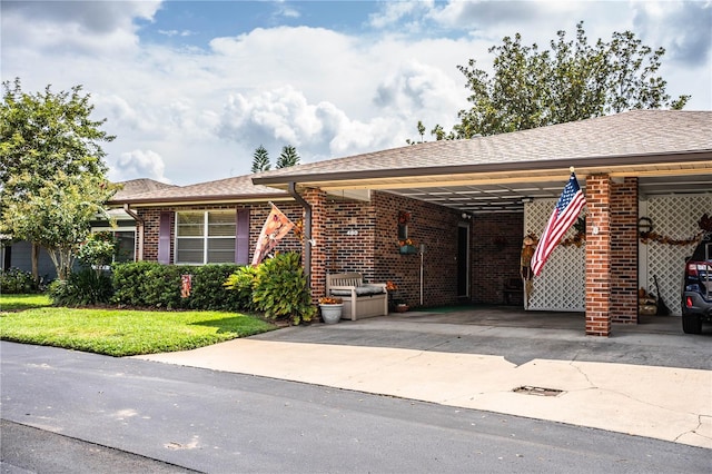 single story home featuring a carport, a front yard, brick siding, and driveway