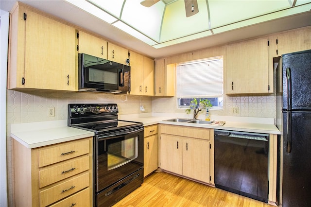 kitchen featuring black appliances, light countertops, a sink, and light wood-style flooring