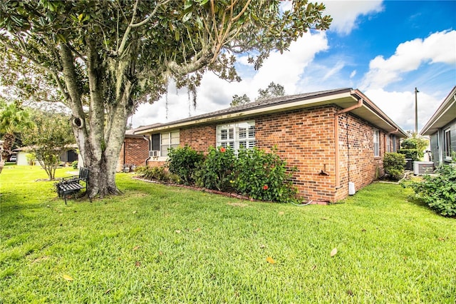 view of home's exterior with brick siding and a lawn