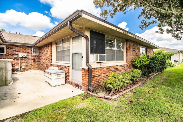 view of front of house featuring cooling unit, a patio area, brick siding, and a front lawn