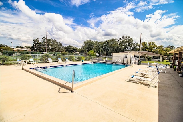 pool with a patio area and fence