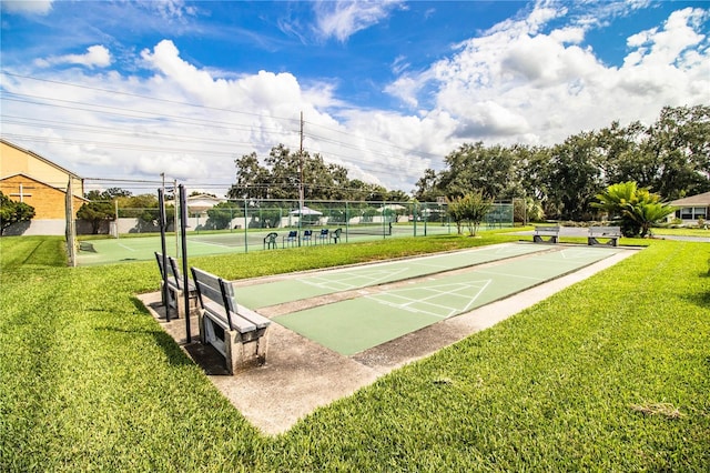 view of home's community with shuffleboard, a lawn, and fence