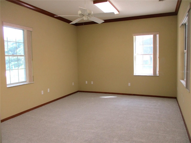 unfurnished room with a wealth of natural light, crown molding, ceiling fan, and light carpet