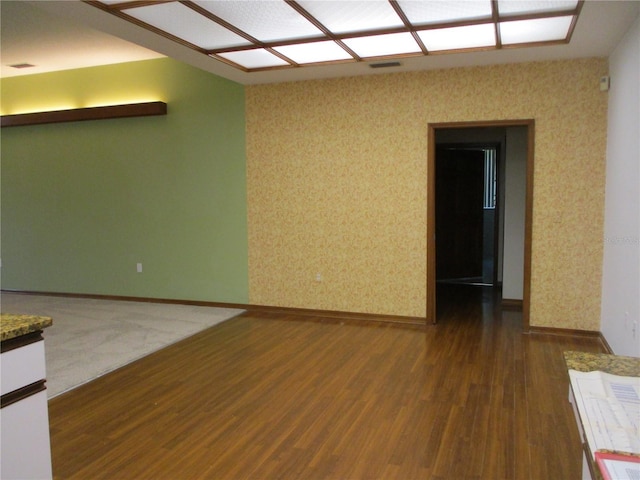 empty room featuring baseboards and dark wood-type flooring