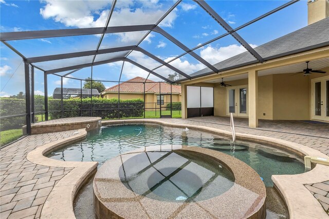 view of swimming pool featuring ceiling fan, glass enclosure, an in ground hot tub, and a patio area