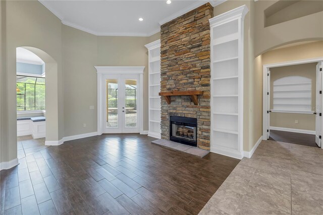 unfurnished living room featuring french doors, a fireplace, plenty of natural light, and crown molding