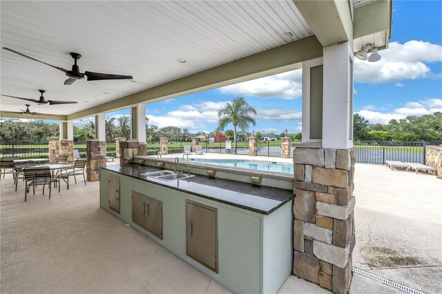 view of patio featuring ceiling fan, a fenced in pool, and sink