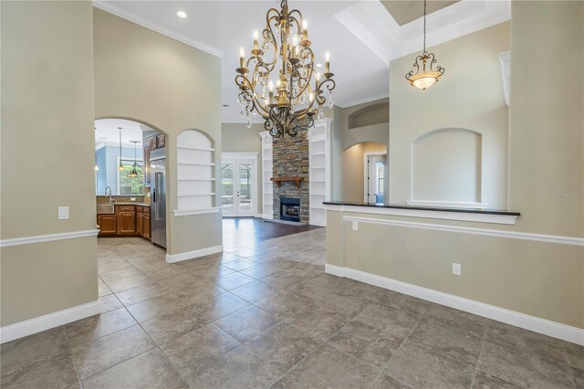 interior space featuring crown molding, a fireplace, a towering ceiling, and built in features