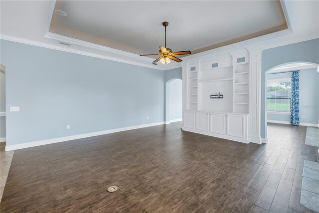 unfurnished living room with ceiling fan, ornamental molding, a raised ceiling, and dark hardwood / wood-style flooring