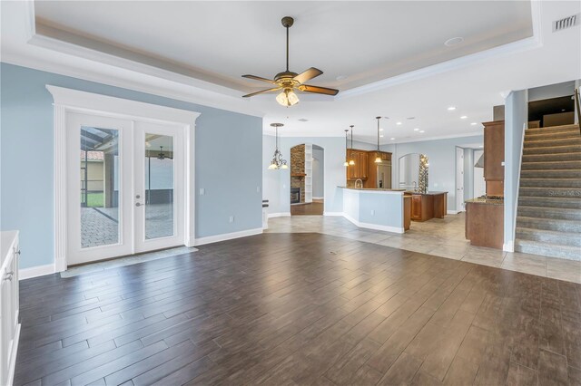 unfurnished living room featuring a tray ceiling, hardwood / wood-style floors, and ceiling fan