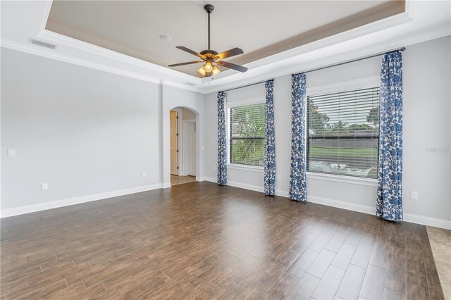 empty room featuring ceiling fan, ornamental molding, a raised ceiling, and dark hardwood / wood-style flooring