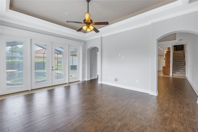 unfurnished room with ceiling fan, a raised ceiling, dark hardwood / wood-style flooring, and a healthy amount of sunlight