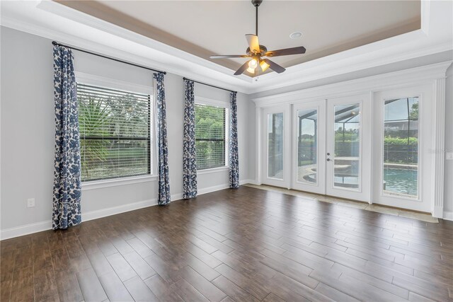 unfurnished room with ceiling fan, a tray ceiling, dark hardwood / wood-style floors, and french doors