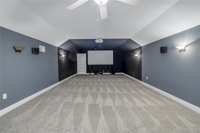 carpeted home theater with ceiling fan and lofted ceiling