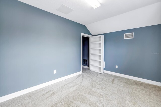 unfurnished bedroom with carpet flooring and vaulted ceiling