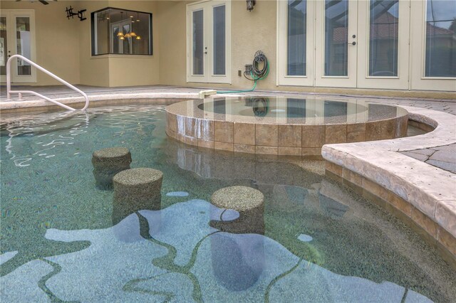 view of swimming pool featuring french doors and an in ground hot tub