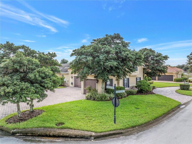 view of property hidden behind natural elements featuring a garage and a front lawn