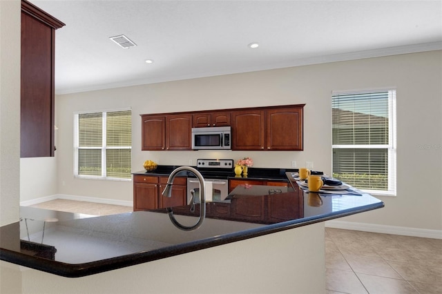 kitchen featuring a wealth of natural light, kitchen peninsula, appliances with stainless steel finishes, and light tile patterned flooring