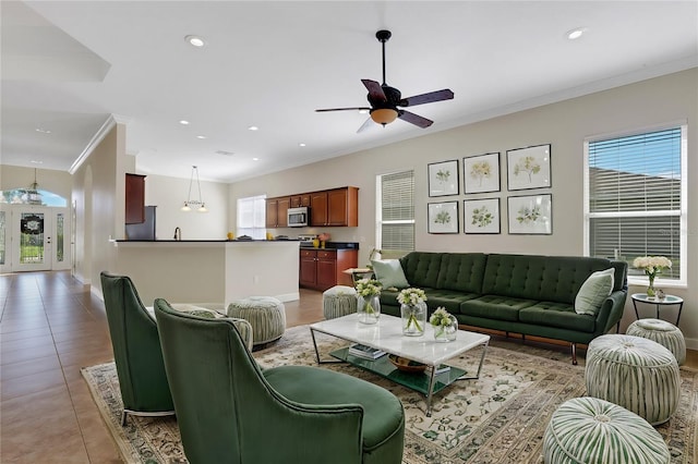 living room with ceiling fan, light tile patterned flooring, and ornamental molding