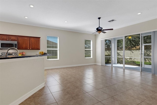 interior space featuring light tile patterned floors, ornamental molding, ceiling fan, and a wealth of natural light