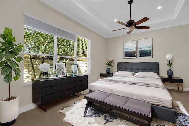 carpeted bedroom featuring multiple windows, a tray ceiling, and ceiling fan