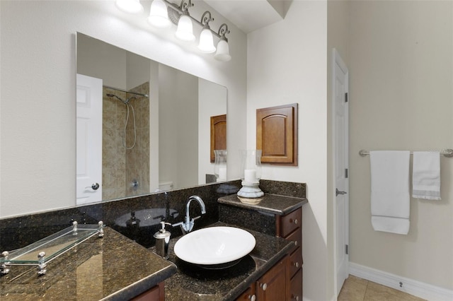 bathroom with a tile shower, tile patterned flooring, vanity, and toilet