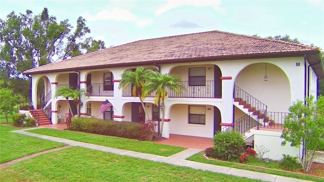 mediterranean / spanish-style home with a balcony and a front lawn