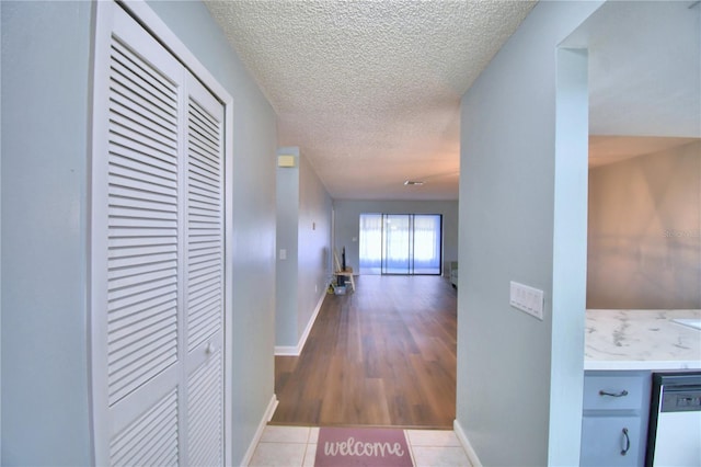 corridor with light wood-type flooring and a textured ceiling