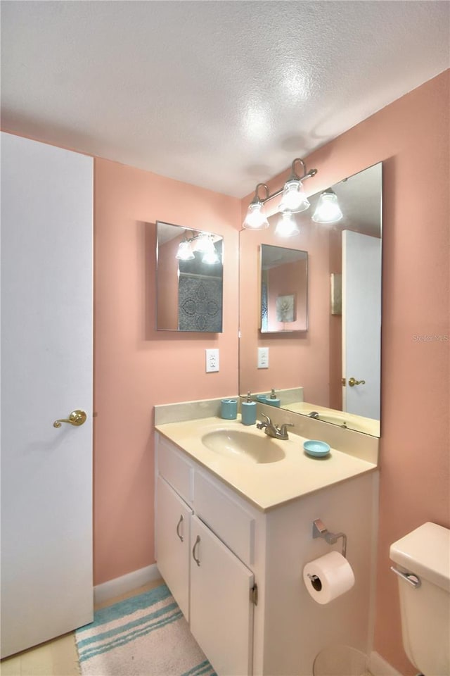 bathroom featuring a textured ceiling, vanity, and toilet