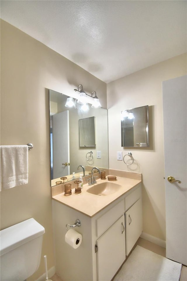 bathroom with a textured ceiling, vanity, and toilet