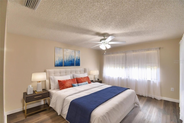 bedroom with ceiling fan, a textured ceiling, and dark hardwood / wood-style flooring