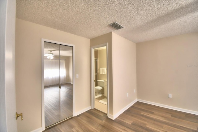 unfurnished bedroom featuring a closet, dark hardwood / wood-style floors, and a textured ceiling