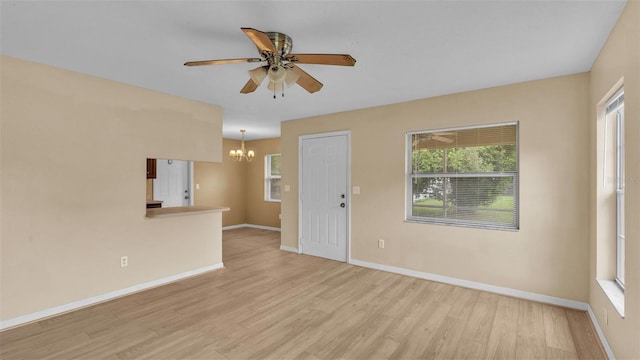 spare room featuring ceiling fan with notable chandelier and light hardwood / wood-style flooring