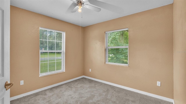 carpeted spare room featuring ceiling fan and plenty of natural light