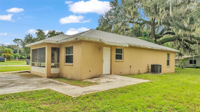 rear view of house with a yard, a sunroom, and central air condition unit