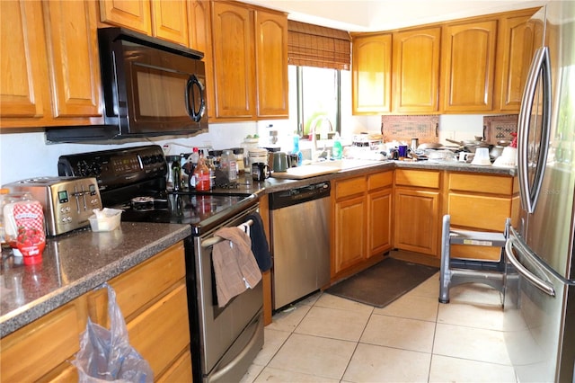 kitchen with appliances with stainless steel finishes, light tile patterned floors, and sink