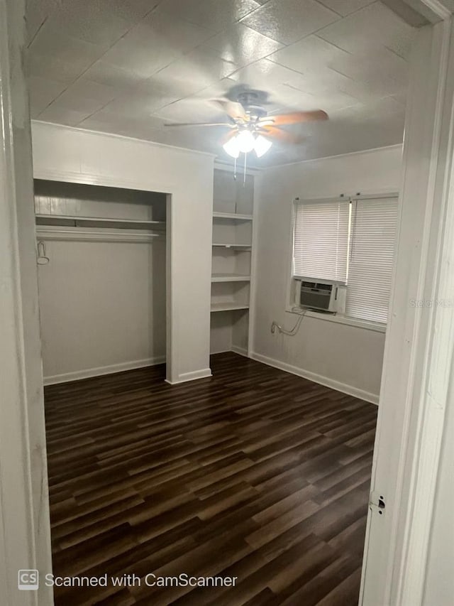 unfurnished bedroom featuring dark hardwood / wood-style flooring, cooling unit, ceiling fan, and a closet