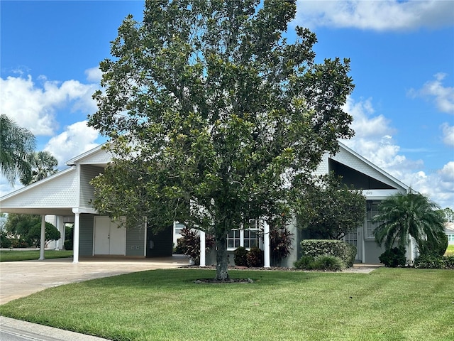 view of property hidden behind natural elements with a front yard and a carport