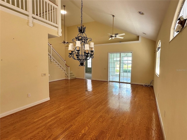 unfurnished room with hardwood / wood-style flooring, ceiling fan with notable chandelier, and high vaulted ceiling