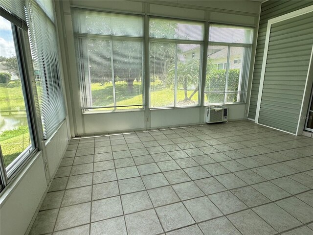 unfurnished sunroom with a wall mounted air conditioner and a healthy amount of sunlight