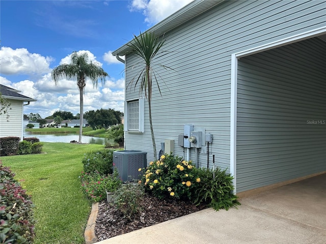 view of side of home with a lawn, a water view, and central AC