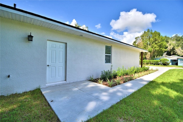 view of side of home with a lawn and a patio area