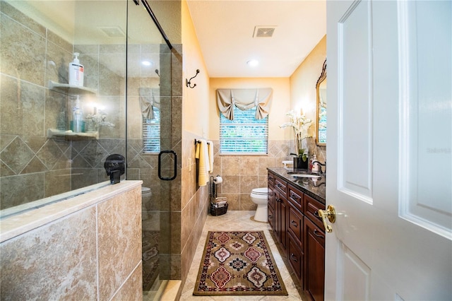 bathroom with vanity, tile patterned floors, toilet, walk in shower, and tile walls