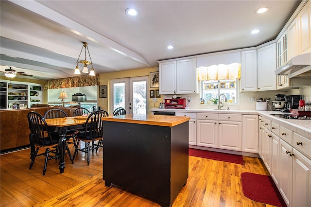 kitchen with a kitchen island, white cabinetry, hanging light fixtures, and wooden counters