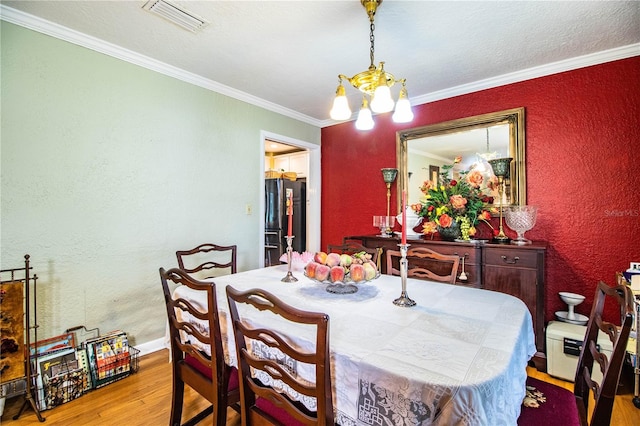 dining room with a chandelier, crown molding, and light hardwood / wood-style flooring