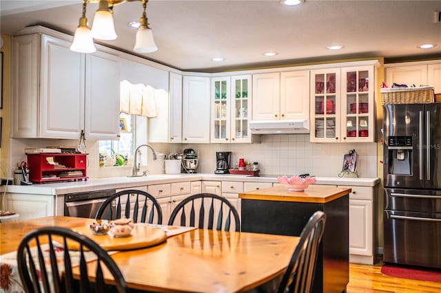 kitchen with refrigerator with ice dispenser, decorative light fixtures, white cabinets, and stainless steel dishwasher